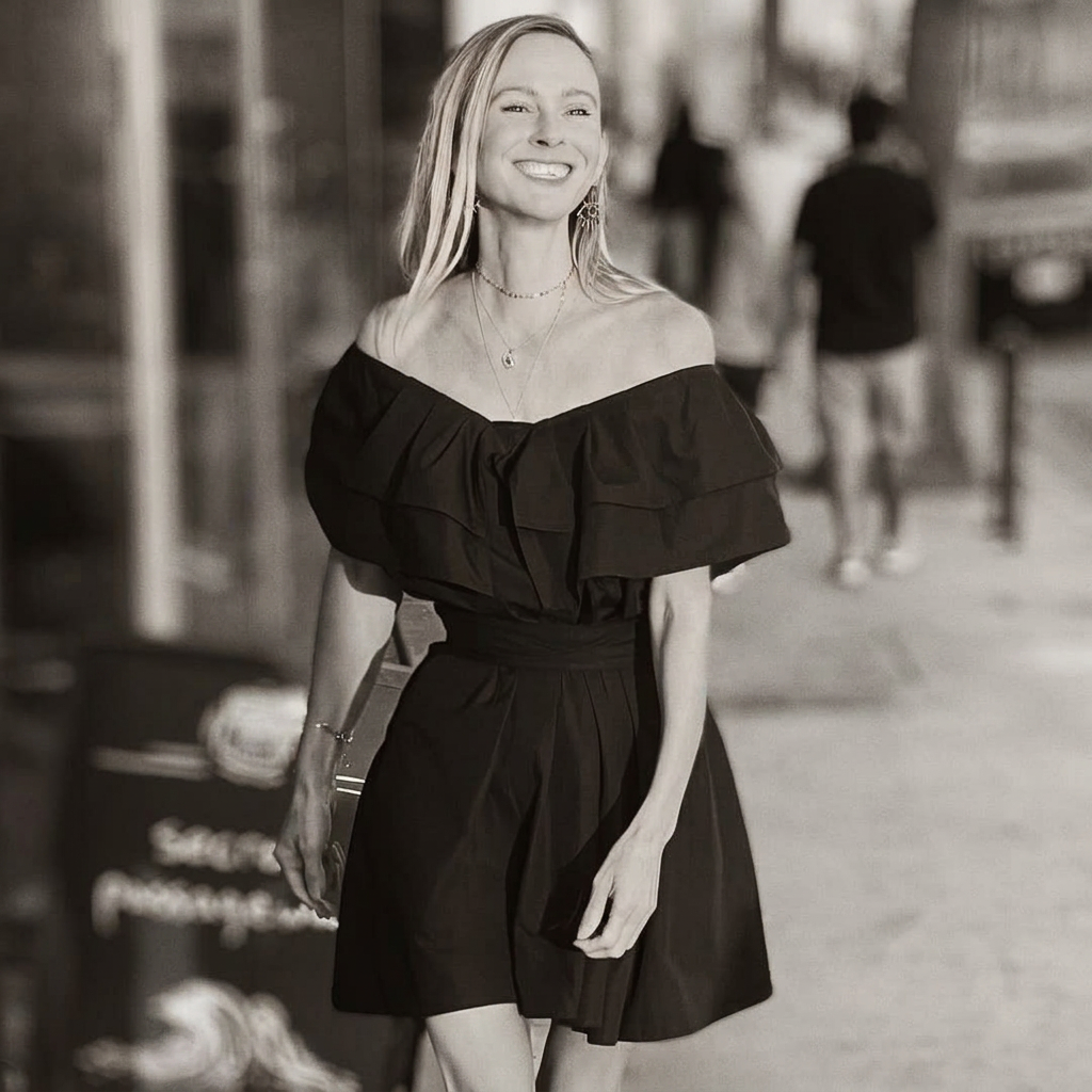 Andrea Christine in a black dress on a downtown street, warm-toned black and white portrait